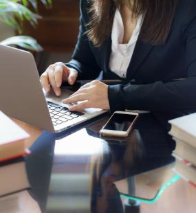 A female conveyancer sits at her desk using her laptop