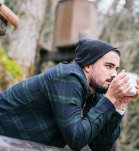 Man drinking coffee on the cottage terrace, melancholic autumn mood 